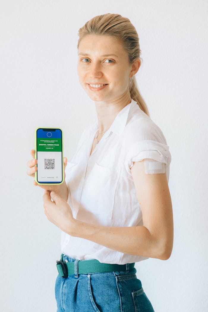 Adult woman holding a phone with a digital vaccine passport on white background.